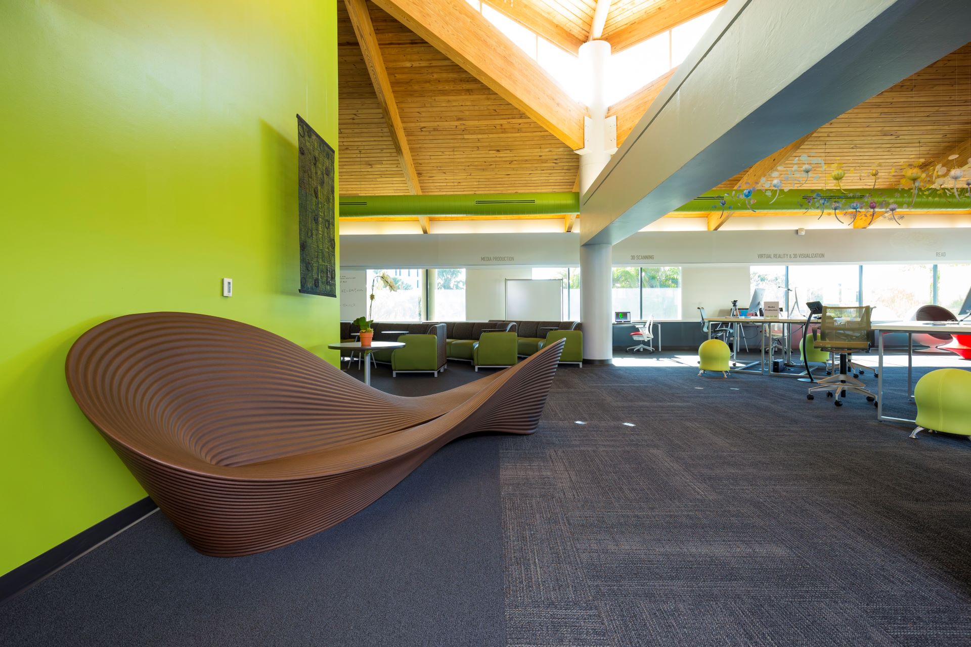 Modern university common area with lime green walls, wooden ceilings, and innovative furniture, including wavy benches and collaborative spaces